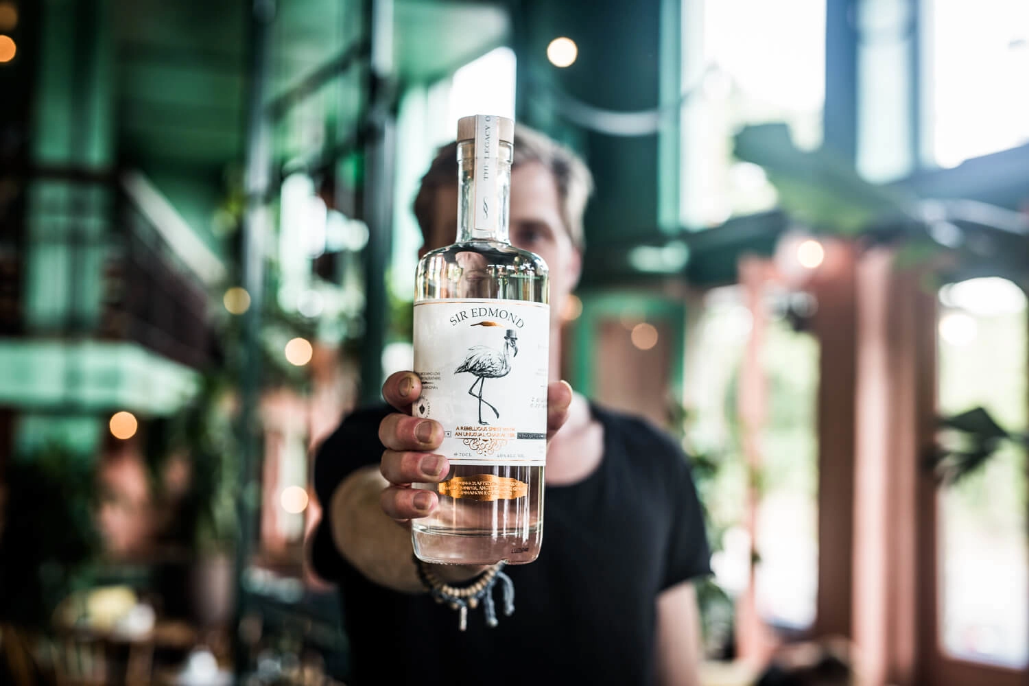 A bottle of Sir Edmon Gin being presented with the surrounding environment blurred.