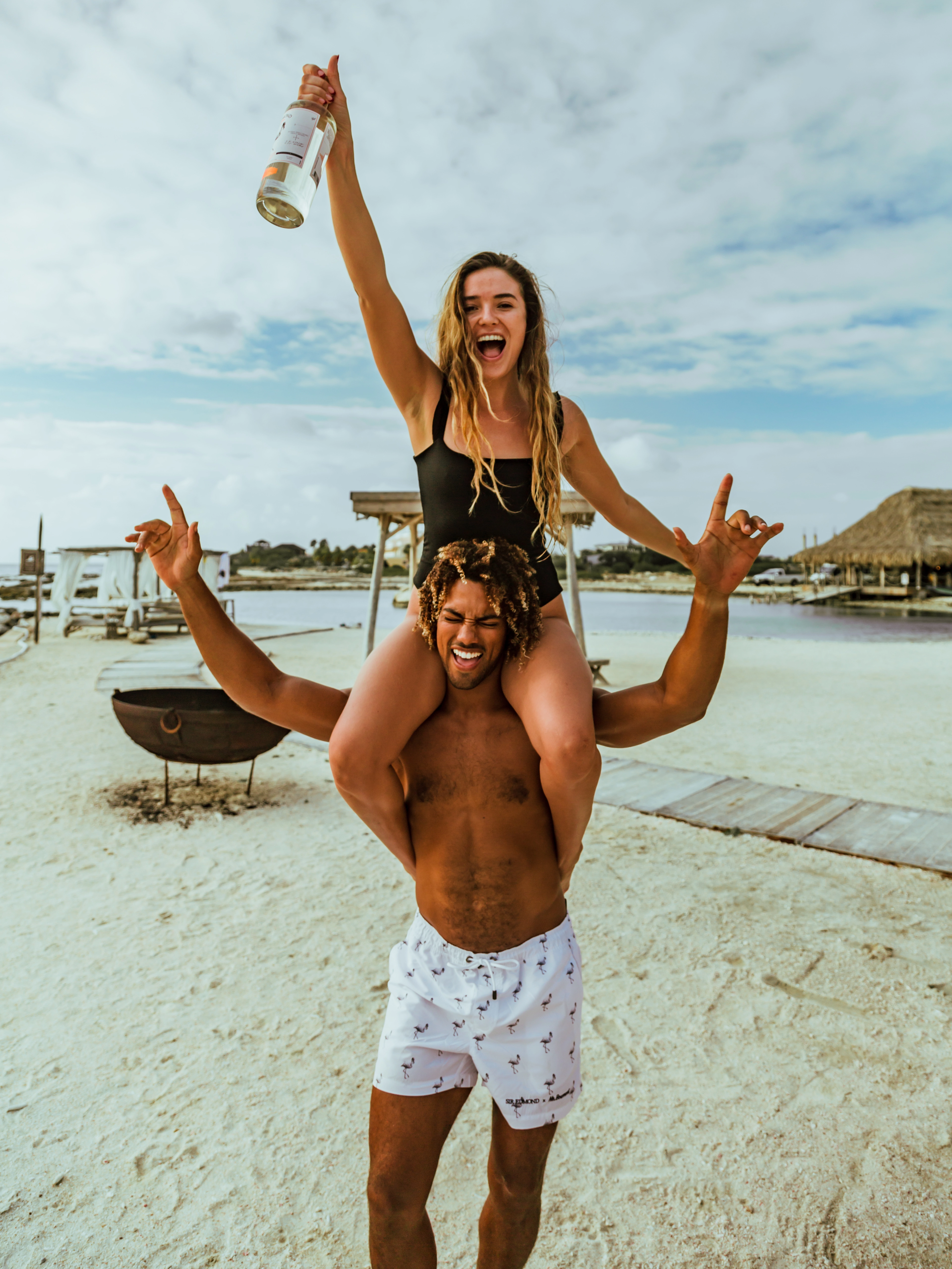 A branding image of a bottle of Sir Edmond gin on the beach being held by a woman.