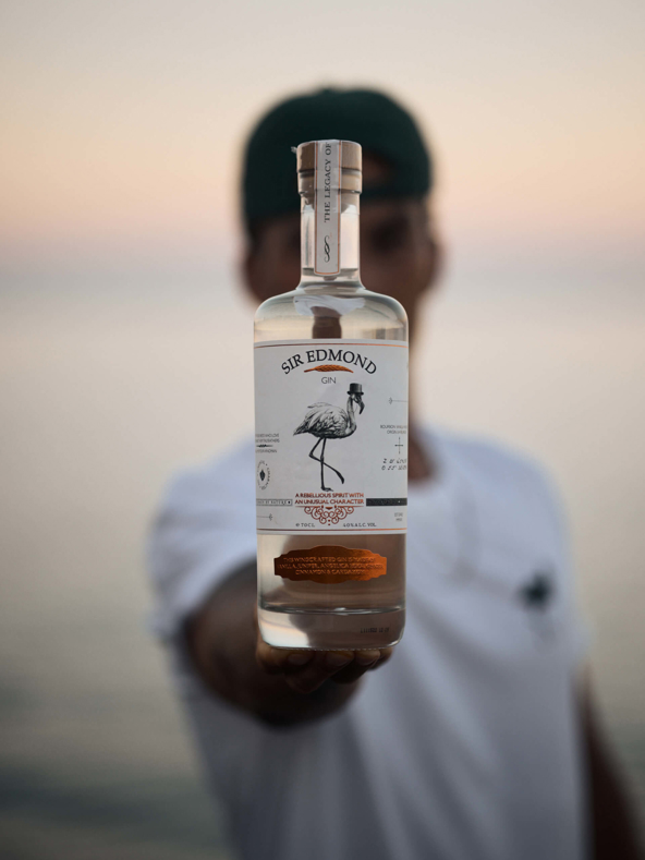A bottle of Sir Edmond gin presented by a man.