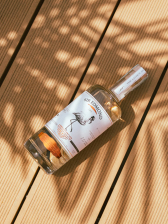 Bottle of Sir Edmond Gin laying on a wooden floor.